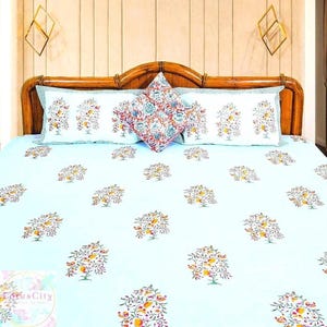 May include: A light blue bed sheet with a floral pattern. The sheet has a white border and is made of cotton. The sheet is on a bed with a wooden headboard and two pillows.