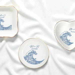 May include: A set of three ceramic mugs with a speckled, matte finish. The mugs are in shades of cream, light gray, and dark gray. Each mug has a simple, minimalist design, perfect for coffee or tea.