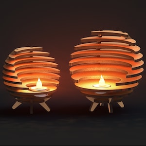 K&ouml;nnte beinhalten: Zwei Kerzenhalter aus Holz mit geometrischem Design. Die Halter sind kugelf&ouml;rmig und haben eine Reihe &uuml;berlappender Ringe. Jeder Halter hat eine kleine Kerze im Inneren, und die Flammen sind sichtbar.