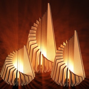 May include: Three wooden lamps with a geometric design. The lamps are made of thin, layered pieces of wood that create a spiral effect. The lamps are lit and casting a warm glow.