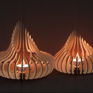 May include: Two wooden candle holders in the shape of a teardrop with intricate cutouts. The candle holders are lit with small tea lights.