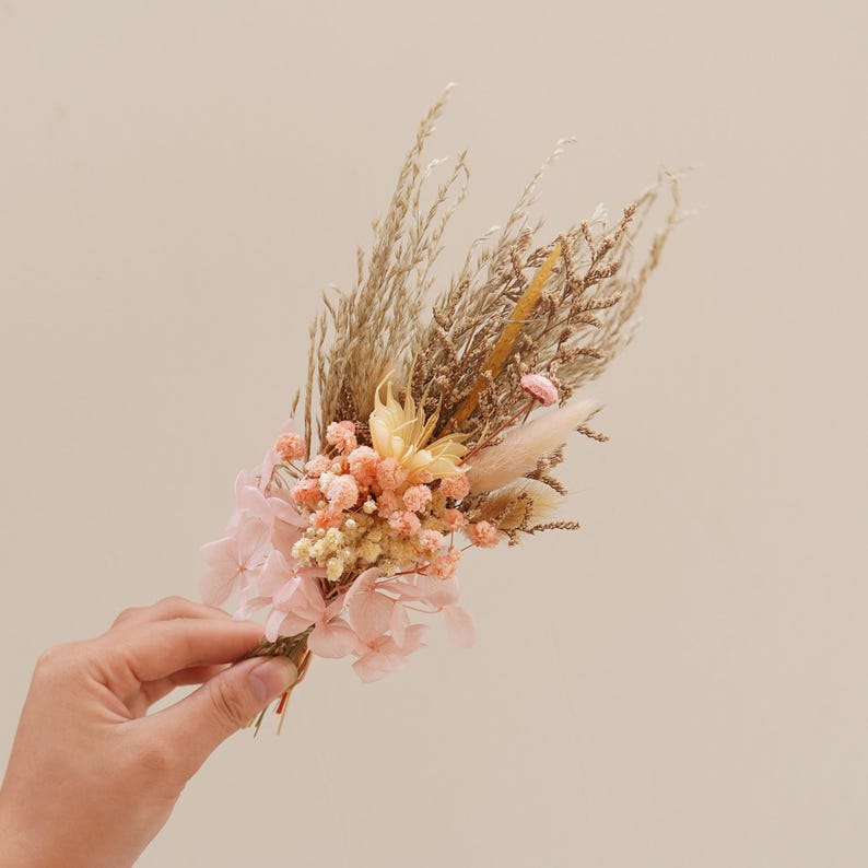 May include: A dried flower bouquet with pink hydrangeas, beige pampas grass, and small pink and white flowers.