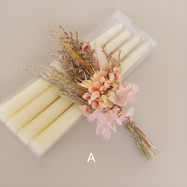 May include: A bouquet of dried flowers in shades of pink and beige, tied with twine, and arranged with a set of six ivory taper candles in a clear plastic package. The package is labeled with the letter "A".