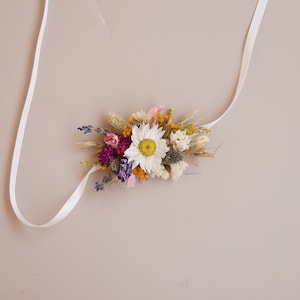 Peut inclure: Ensemble de trois mugs en céramique avec un glaçage moucheté de couleur crème. Chaque mug présente un motif peint à la main différent : une feuille bleue et verte, une fleur jaune et une baie rouge. Les mugs ont une forme simple et arrondie.