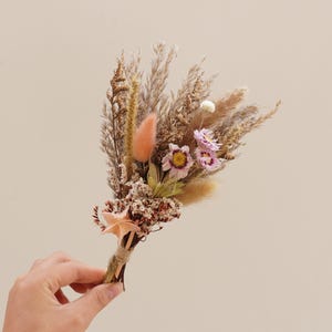May include: A small bouquet of dried flowers with pink, purple, and white blooms, and brown dried grasses.