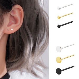 Puede incluir: Un conjunto de seis pendientes de botón en diferentes colores y estilos. Los pendientes se muestran sobre un fondo blanco. Los pendientes son todos pequeños y simples, y serían una gran adición a cualquier colección de joyas.