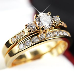 May include: A gold wedding band set with a large, sparkling diamond and smaller diamonds encircling the band.