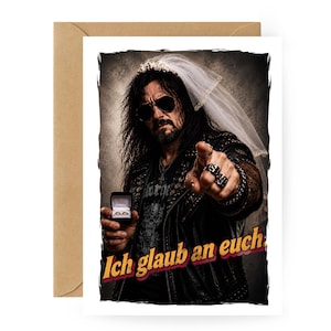 Könnte beinhalten: Grußkarte mit einem Mann in Lederjacke, Sonnenbrille und Schleier, der eine Ringbox hält und zeigt. Der Text "Ich glaub an euch" ist in roter und gelber Schrift dargestellt. Die Karte befindet sich in einem braunen Umschlag.