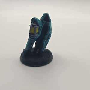 May include: A teal-colored figurine of a cloaked figure holding a lantern. The figure is standing on a black, circular base. The lantern has yellow and purple accents. The figurine is likely for tabletop gaming or as a decorative item.