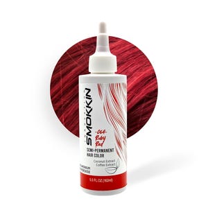 May include: A bottle of Smokkin semi-permanent hair color in Ruby Red. The white bottle has a nozzle and is labeled with product information, including "-064- Ruby Red" and "5.5 FL.OZ. (162ml)." The background features a swatch of red hair.
