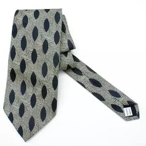 May include: A black and cream patterned tie with a geometric design. The tie is made of silk and has a pointed tip.