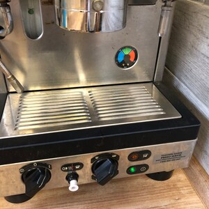 Puede incluir: Una máquina de espresso de acero inoxidable con una bandeja de goteo negra y botones de control. La máquina tiene un manómetro con una aguja verde, azul y roja. La máquina tiene una pegatina que dice "CLASSICA MOD. PRESO SOFTIE PAOLO 600 000 147".