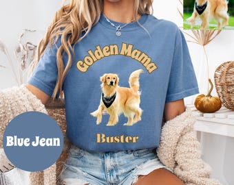 May include: A blue jean colored t-shirt with the text "Golden Mama" above a golden retriever illustration wearing a bandana. The dog's name "Buster" is below the illustration. The shirt has short sleeves.