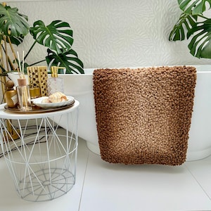 Op de afbeelding: Een bruine en beige badmat met een textuur, pluche oppervlak. De mat is gemaakt van een zacht, absorberend materiaal en is perfect om elke badkamer een vleugje stijl te geven.