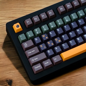 May include: A black mechanical keyboard with brown, green, and orange keycaps. The keyboard has a black frame and a black and orange space bar.