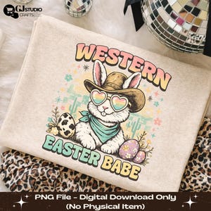 Może przedstawiać: Beżowa bluza z kapturem z kreskówkowym królikiem w kapeluszu kowbojskim i okularach przeciwsłonecznych w kształcie serca. Tekst "WESTERN EASTER BABE" jest wyświetlany w kolorowych literach, z kaktusami i pisankami. Pobranie cyfrowe.