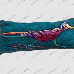 May include: A teal blue pillow with a colorful embroidered roadrunner design. The roadrunner is running to the right and has a long, thin beak. The pillow is made of a soft, plush fabric.