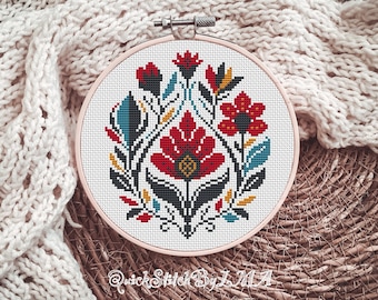 May include: A white embroidery hoop with a colorful floral design. The design features red, yellow, blue, and black flowers and leaves. The hoop is on a woven surface.