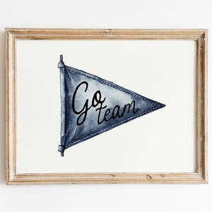 Pode incluir: Impress&atilde;o em aquarela de uma bandeira de bandeirola azul com as palavras "Go team" em escrita preta. A bandeira &eacute; emoldurada em uma moldura de madeira marrom clara, em um fundo branco. Uma pe&ccedil;a decorativa para um f&atilde; de esportes.