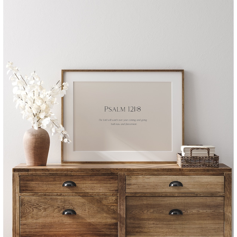 May include: A framed print with a beige background and the text "PSALM 121:8" and the quote "The lord will watch over your coming and going both now and forevermore".