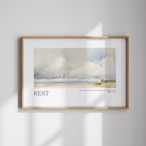 May include: A framed print with a watercolor painting of a cloudy sky over a body of water. The text "REST" is at the bottom of the image, along with the quote "Come to me, all you who are weary and burdened, and I will give you rest. Matthew 11:28"