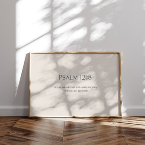 May include: A framed print with a beige background and a gold frame. The print features the text "PSALM 121:8" and the quote "The Lord will watch over your coming and going both now and forevermore."