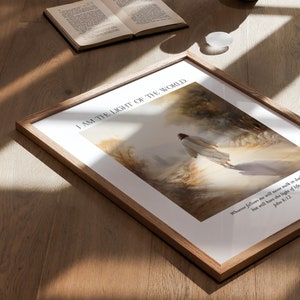 Puede incluir: Impresi&oacute;n art&iacute;stica enmarcada con tem&aacute;tica religiosa. La obra representa una figura con t&uacute;nica blanca caminando hacia una luz brillante. El texto "I AM THE LIGHT OF THE WORLD" est&aacute; en la parte superior, con un vers&iacute;culo b&iacute;blico en la parte inferior. El marco es de madera clara.