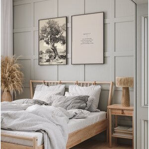 Pode incluir: Um quarto com uma estrutura de cama de madeira, roupa de cama branca e duas impress&otilde;es emolduradas na parede. Uma impress&atilde;o &eacute; uma fotografia em preto e branco de uma &aacute;rvore, e a outra impress&atilde;o tem um vers&iacute;culo b&iacute;blico. H&aacute; uma mesa de cabeceira de madeira com uma l&acirc;mpada em cima.