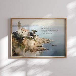 May include: A framed print featuring a watercolor painting of a coastal scene. A white building with a tower sits atop a cliff overlooking the ocean. The text "MATTHEW 7:24" and a Bible verse are printed on the right side.