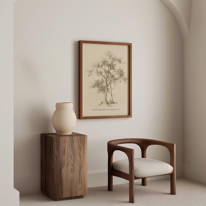 Puede incluir: Una impresi&oacute;n enmarcada de un dibujo a l&aacute;piz de un &aacute;rbol con el texto "Rooted and grounded in love, 1 Corinthians 13:13". La impresi&oacute;n est&aacute; colgada en una pared blanca sobre una mesa auxiliar de madera con un jarr&oacute;n de cer&aacute;mica beige. Una silla de madera con un coj&iacute;n blanco est&aacute; en primer plano.