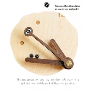 May include: A wooden clock with a unique design featuring a soot sprite as the second hand. The clock face is made of light wood and the hands are made of dark wood. The soot sprites are very shy and often hide away. It is said that only kind-hearted children can see them.