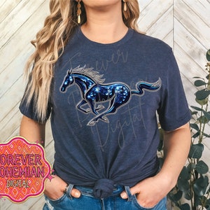 May include: A navy blue t-shirt featuring a blue and silver sparkly horse design. The shirt has a crew neck and short sleeves. The design is centred on the shirt and depicts a running horse with a flowing mane.