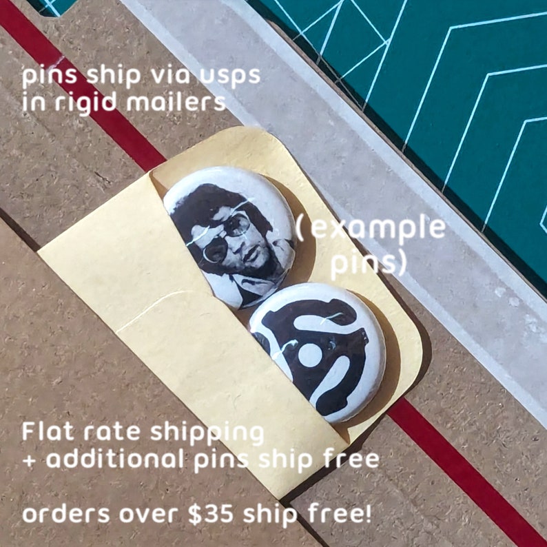May include: Two round pins with black and white designs are displayed in a small tan envelope. One pin features a portrait of a person wearing sunglasses, and the other has a graphic design. The text "(example pins)" is visible.