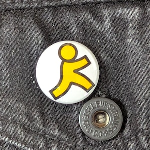 May include: A white button with a yellow figure in motion, set against a dark denim background. A silver button with the text "LEVI STRAUSS & CO." is also visible. The yellow figure is outlined in black.