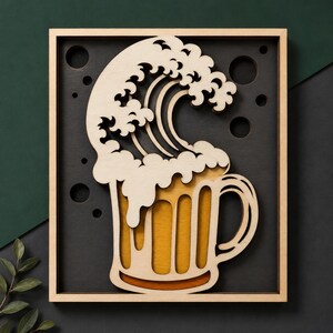 Può includere: Arte da parete in legno raffigurante un boccale di birra con un disegno a onda. Il boccale di birra è riempito con un liquido dorato e sormontato da bolle bianche schiumose. L'onda è anch'essa in legno ed è posizionata sopra il boccale. L'opera è incorniciata.