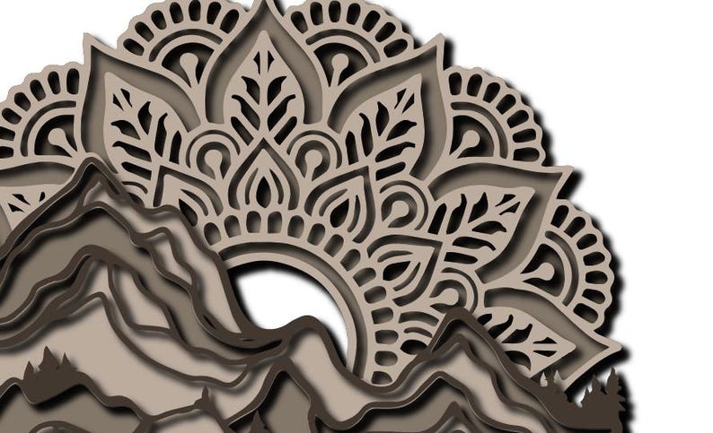 May include: A multi-layered laser-cut wall art piece featuring a beige and dark brown mountain range silhouette at the bottom, topped with an intricate, symmetrical mandala pattern in shades of beige and brown, creating a dimensional effect.