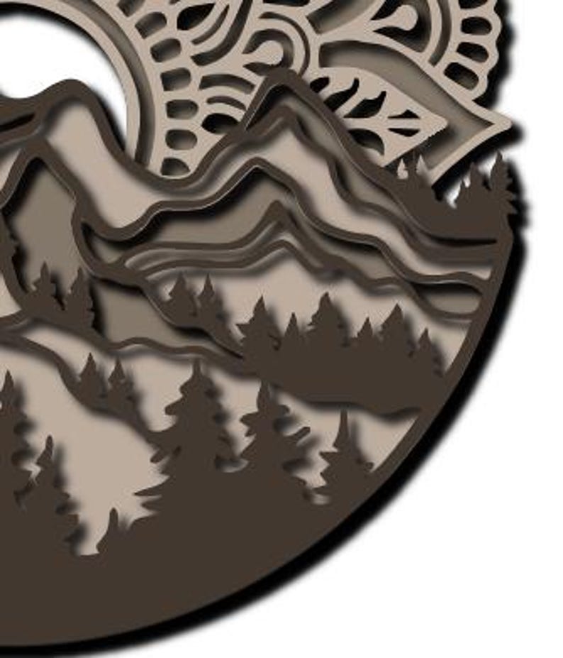 May include: A multi-layered circular wall art piece featuring a dark brown and beige mountain landscape with a forest of pine trees in the foreground and an intricate, mandala-inspired sun pattern at the top, all crafted with cut-out details.