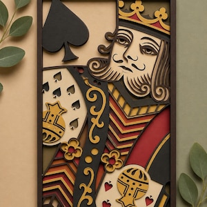 May include: A framed, multi-layered paper art piece depicting the King of Spades playing card. The artwork features a detailed design with black, red, yellow, and tan colors. The king wears a crown and has a long mustache and beard.