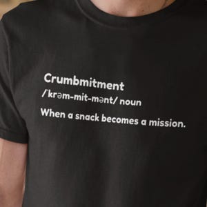 May include: Black t-shirt with the word "Crumbmitment" in white, along with its pronunciation and definition: "When a snack becomes a mission."