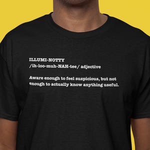 Pode incluir: Camiseta preta com texto branco. O texto diz "ILLUMI-NOTTY /ih-loo-muh-NAH-tee/ adjetivo" seguido de uma definição: "Consciente o suficiente para se sentir desconfiado, mas não o suficiente para realmente saber algo útil."