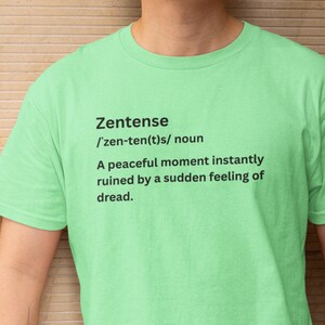 May include: A light green t-shirt with the word "Zentense" and its pronunciation, followed by a definition: "A peaceful moment instantly ruined by a sudden feeling of dread."