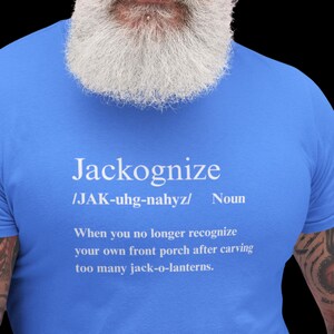 May include: A blue t-shirt with the word "Jackognize" printed in white, along with a definition. The definition explains the term as the inability to recognize your porch after carving too many jack-o-lanterns.
