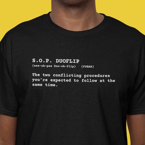 Puede incluir: Camiseta negra con texto blanco. El texto dice "S.O.P. DUOFLIP (ess-oh-pee Doo-oh-flip) (FUBAR)". Debajo, la frase "Los dos procedimientos contradictorios que se espera que siga al mismo tiempo."