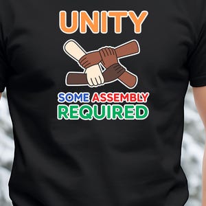 May include: Black t-shirt with the word "UNITY" in orange and white, and the phrase "SOME ASSEMBLY REQUIRED" in green and white. The shirt features a graphic of interlocked hands in various skin tones.