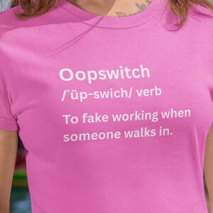 May include: Pink t-shirt with the word "Oopswitch" and its phonetic pronunciation in white text. Below, the definition: "To fake working when someone walks in."