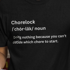 May include: Black t-shirt with the word "Chorelock" and its pronunciation, followed by a definition: "Doing nothing because you can't decide which chore to start."