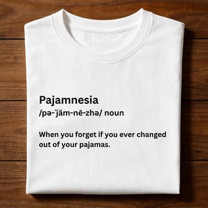 May include: White t-shirt with the word "Pajamnesia" and its pronunciation, along with the definition: "When you forget if you ever changed out of your pajamas."