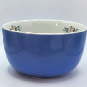 May include: A blue ceramic bowl with a white rim and floral design. The bowl is approximately 4 inches in diameter.