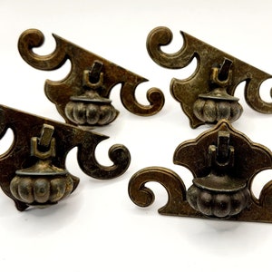 May include: Four antique brass cabinet knobs with ornate scrollwork and a round, textured knob. The knobs are in a distressed finish.