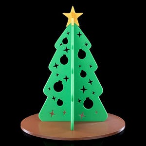 K&ouml;nnte beinhalten: Eine gr&uuml;ne, dreidimensionale Weihnachtsbaumdekoration mit ausgestanzten Stern- und Kugelformen. Der Baum ist mit einem gelben Stern gekr&ouml;nt und steht auf einem runden braunen Sockel, was ein strukturiertes und geschichtetes Erscheinungsbild ergibt.